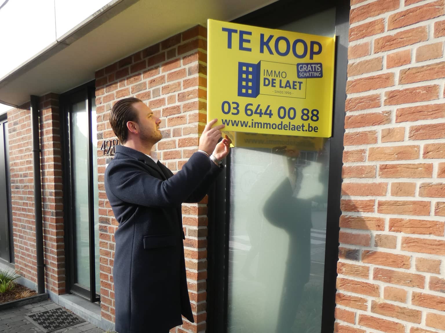 Immo De Laet vastgoedmakelaar hangt bord aan huis in Antwerpen